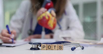 Wooden blocks display POTS near heart model and stethoscope