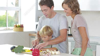 Father teaching son to slice vegetables