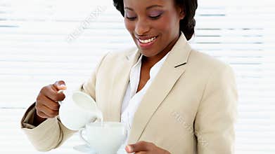 Businesswoman pouring milk into her cup