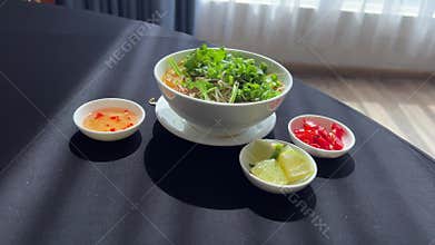 add herbs to the soup Freshly prepared Pho Bo noodles served in a bowl with beef, herbs, and garnishes