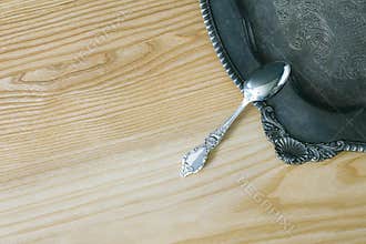 Silver Spoon On Floral Vintage Salver On Wooden Surface