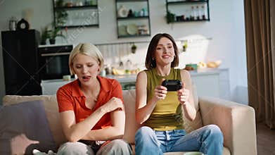 Emotional players competing online sitting sofa with console at home closeup