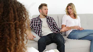 Arguing young couple sitting on couch