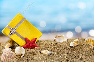 Gold gift box on sand with summer sea