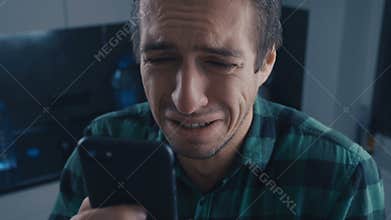 Depressed man reading bad message on his smartphone. Drama concept.