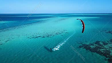 Aerial view young man kite surfing in tropical blue ocean