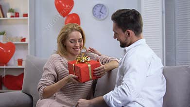Boyfriend giving surprised happy lady gift for st Valentines day, happy couple