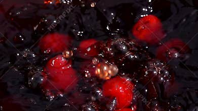 Ripe red raspberries fall into juice