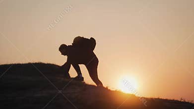 Silhouette young tourist climbs the mountain. Hands of the climber hanging on rock. Rock climbing, mountain climbing