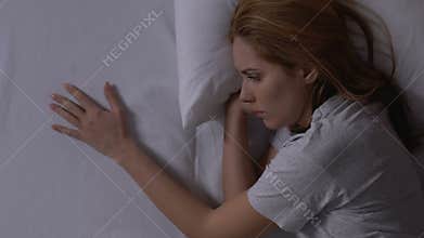 Crying woman touching opposite side of bed, missing boyfriend after break up