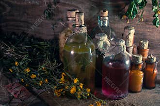A witchery stuff: multiple tincture bottles, bunches of dry healthy herbs, stack of ancient ritual books, amulets, candles...