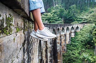 Woman sits on the Demodara nine arches bridge in Ella, Sri Lanka