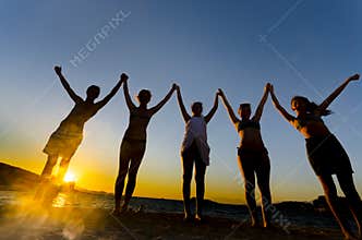 Silhouette of teens at sunset on the beach, happiness concept