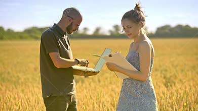 Agronomists working in wheat field. Agriculture scientist using computer