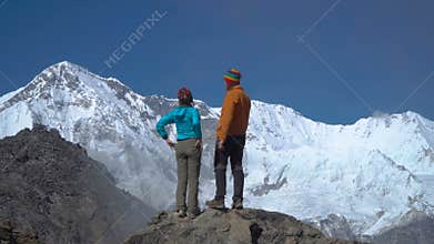 A man helps a girl to climb a rock