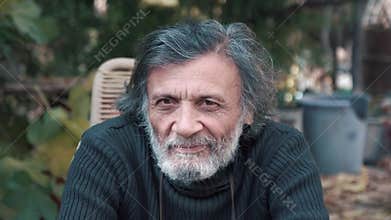 A gray-haired grandfather looking at the camera and winks