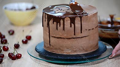 Confectioner pours chocolate on cake.