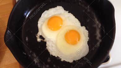 Eggs Frying in Cast Iron Pan.