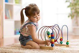 Kid girl plays with educational toy indoors
