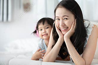 Happy asian family mother with daughter playing on bed with smil