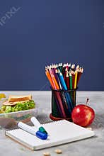 Back to School concept, school supplies, biscuits, packed lunch and lunchbox over white chalkboard, selective focus.