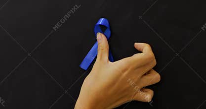 Hand attaches blue awareness ribbon