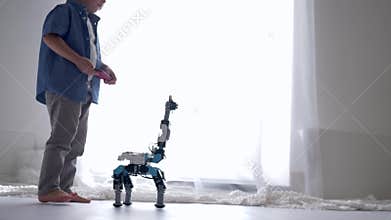Innovation technology in childhood, cute kid boy is played by robot toy on remote control using mobile phone