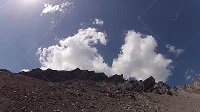 Timelapse of clouds moving on blue skies behind rocks
