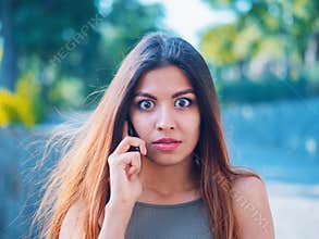 Surprised girl heard stunning news on phone. Gossip with girlfriend. Woman speaks on smartphone. Beautiful businesswoman