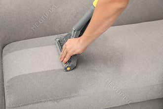 Janitor removing dirt from sofa with upholstery cleaner