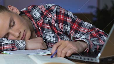 Young guy napping at school desk, educational boredom, examination tiredness