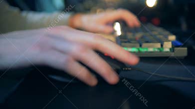Young gamer uses keyboard and a mouse. Cybersport concept.
