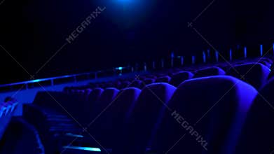 Dark, empty cinema hall with comfortable seats in blue light. Close up for seat rows in movie theatre.