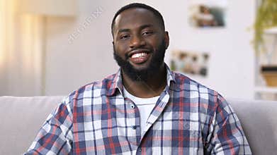 Smiling african american man ready for flat cleanup, holding cleaning products