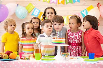 Kids celebrate birthday party and blow candles on festive cake