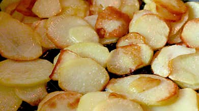 Sliced potato chips that look like chips are fried in a frying pan to a golden brown color. Oil boils on the bottom. Close.