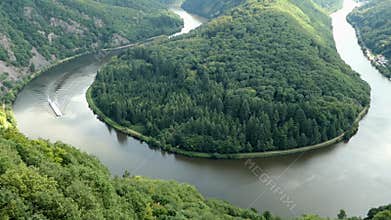 View over the Saar river loop next to Mettlach in Saarland Germany. tourist boat driving on river.