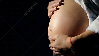 Close-up of big belly pregnant girl in the dark.