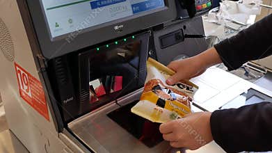 Motion of woman scanning cookie at self-check out counter