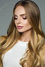 Perfect woman with thick blonde hair and white blouse over grey background.