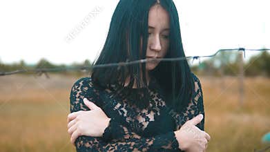 Girl brunette refugee behind barbed wire camp slow motion video. the concept of freedom is upset Woman hands and barbed