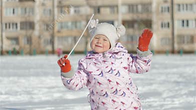 Smiling little girl running outdoors on snowy stadium near school