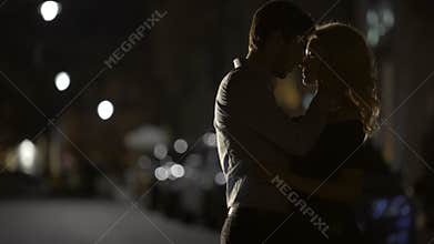 Silhouettes of loving couple embracing each other in the street, relationship
