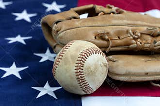 Close up of a used baseball and mitt on United States flag