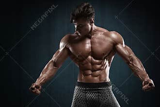 Handsome muscular man on wall background, shaped abdominal. Strong male naked torso abs