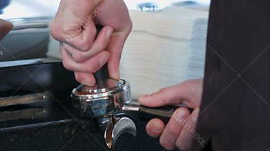 Barista presses ground coffee using tamper