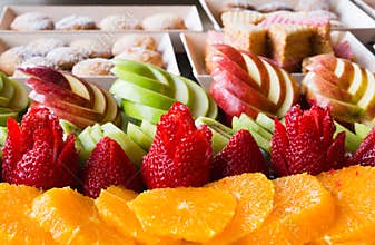 Apples with strawberry kiwi oranges and cookies are laid out for