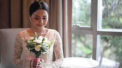 Asian bride in lace dress holding and smell beautiful white wedding flowers