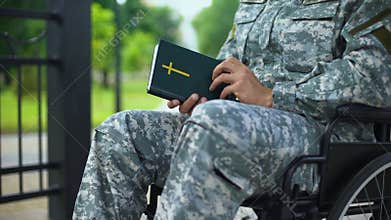 Disabled serviceman in wheelchair reading bible, religious faith health recovery