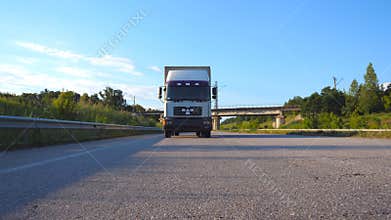 White truck driving on a highway. Lorry rides through the countryside with beautiful landscape at background. Slow
